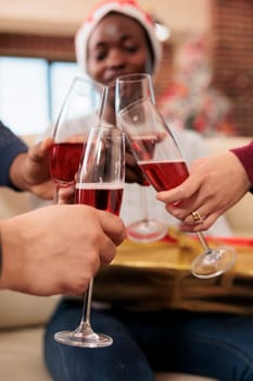 Coworkers celebrating christmas in office and clinking glasses of sparkling wine closeup. Cheerful company employees hands holding alcohol drink and toasting to new year holiday