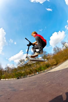 boy jumping with a scooter over a funbox