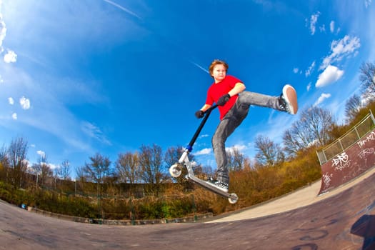 Boy riding a scooter is jumping at a scooter park