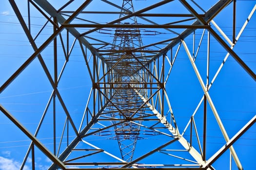 Steel electricity pylon on bright blue sky