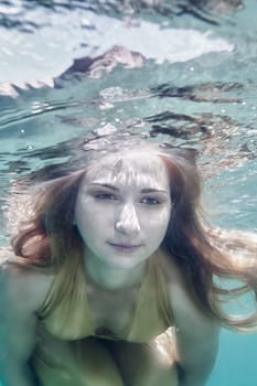 Young beautiful woman in golden dress underwater