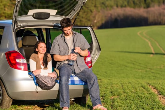 Happy camping couple lying inside car summer sunset countryside