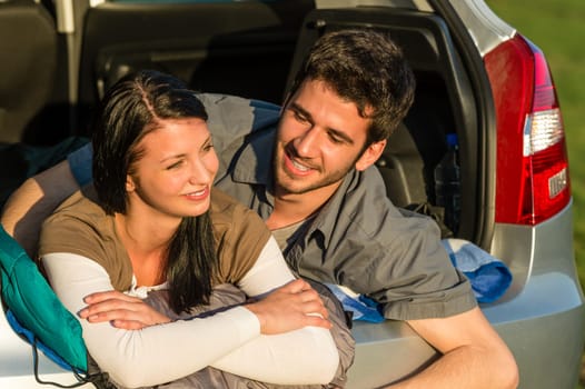 Camping young couple hugging together in car summer sunset