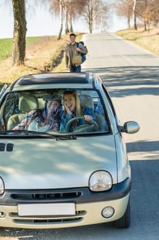 Two women happy in car taking handsome hitch-hiker road trip