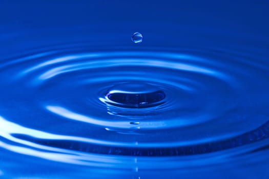 close-up of a droplet, falling in the blue water