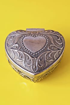 silver ornate heart isolated on yellow background
