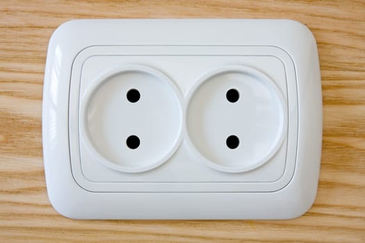close up of white electric outlet on wooden wall
