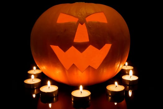halloween pumpkin and burning candles in a darkness