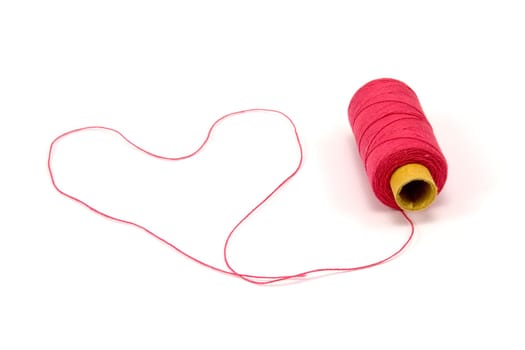 Heart shape made of red thread with spool