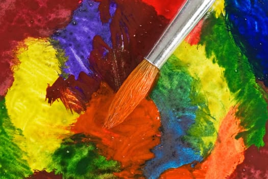 close up of paintbrush on colorful painted paper