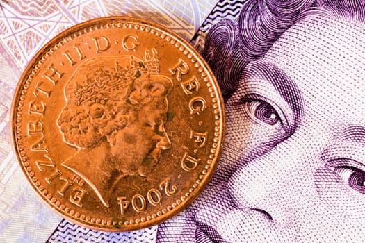 one penny coin on a twenty pounds banknote