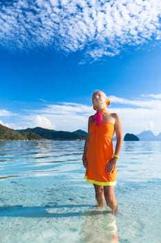 Woman in orange dress on the tropical beach