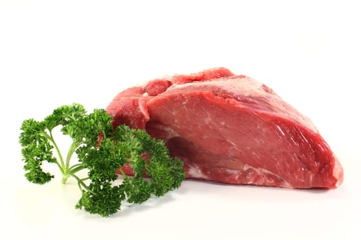 a piece of raw roast pork with parsley