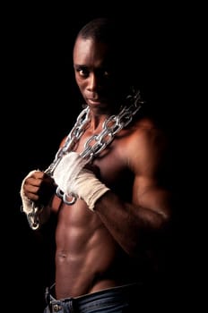 Beautiful and muscular black man with chains in dark background