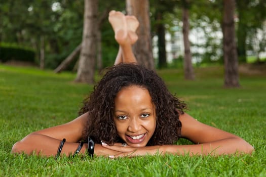 Young beautiful african american woman lying down on the grass