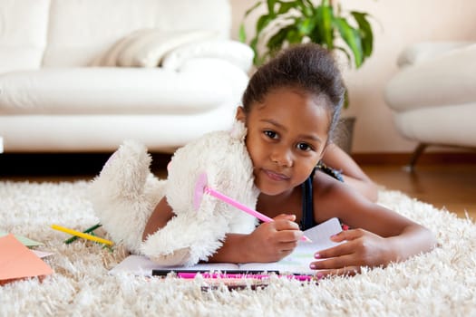 Little African Asian girl  drawing, lying on the floor