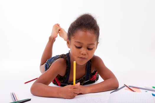 Little African Asian girl  drawing, lying down on the floor
