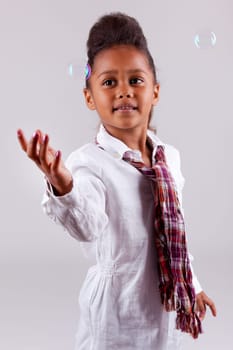 Cute little African American girl blowing soap bubbles
