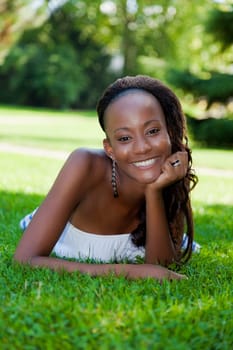 Smiling young african american girl lying down on the grass