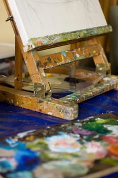 Atelier. Palette with colors, easel in the background