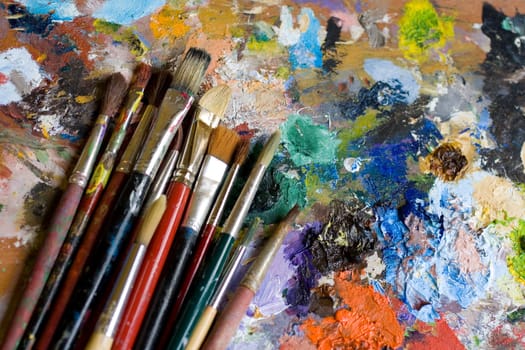 Paintbrushes used and dirty color. Palette on the background