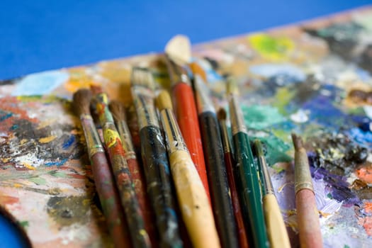 Paintbrushes used and dirty color. Palette on the background
