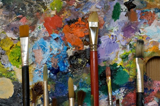 Paintbrushes used and dirty color. Palette on the background