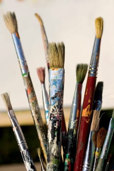 Paintbrushes and painted canvas in the background