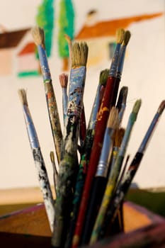 Paintbrushes and painted canvas in the background