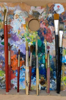 Paintbrushes used and dirty color. Palette on the background