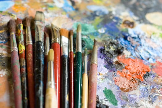 Paintbrushes used and dirty color. Palette on the background