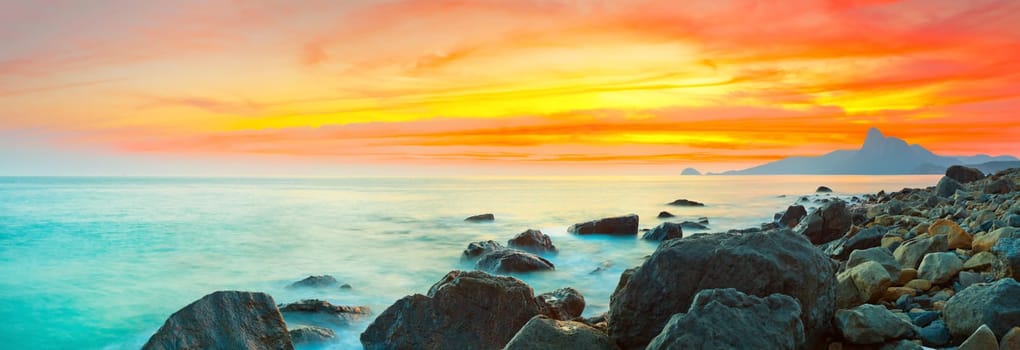 Sunset over the sea. Stone on the foreground. Panorama