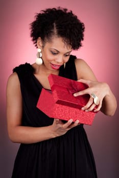 Portrait of a happy young African American woman opening a gift