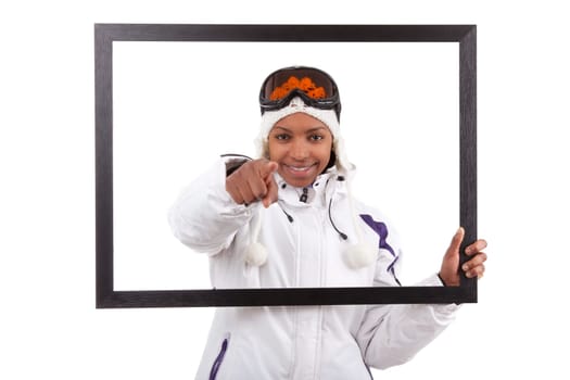Young smiley woman in ski gears  holding a picture frame, isolated on white background