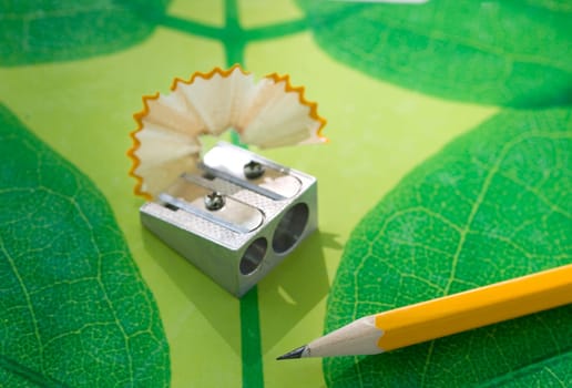 Pencil sharpneer and pencil on green texture