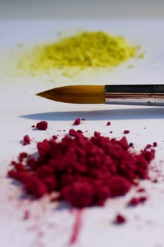 Red and bordeaux pigments and brush on a white backround