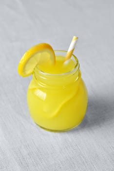 Lemonade in a Mason Jar with yellow striped straw and lemon wedge
