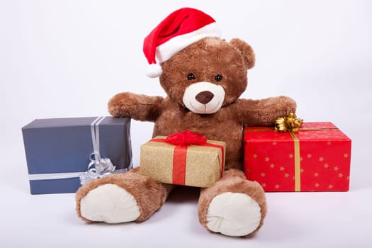 Seated teddy bear wearing a santa hat, over a white background