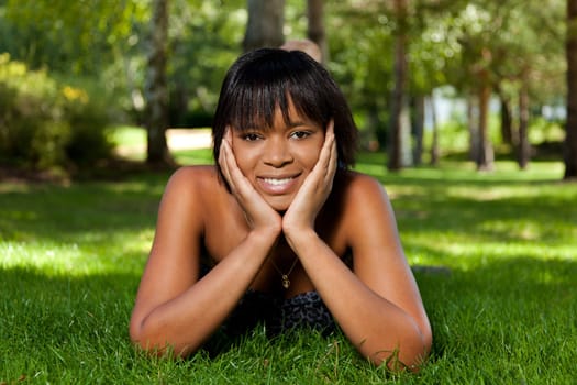 Young beautiful african american woman lying down on the grass