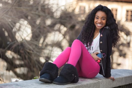 Outdoor of a  portrait happy young african american teenage girl listening to music