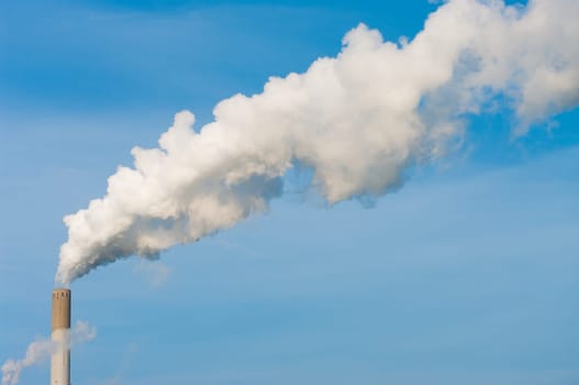 smoking chimney of a power plant against a blue sky