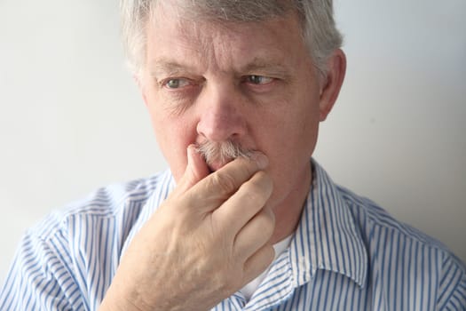 an older man nervously tends to his facial hair