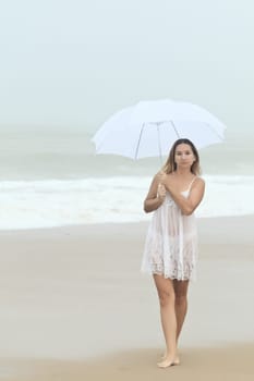 Beautiful woman near the stormy ocean at rain