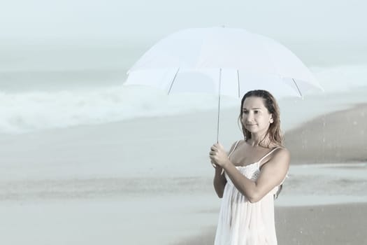 Beautiful woman near the stormy ocean at rain