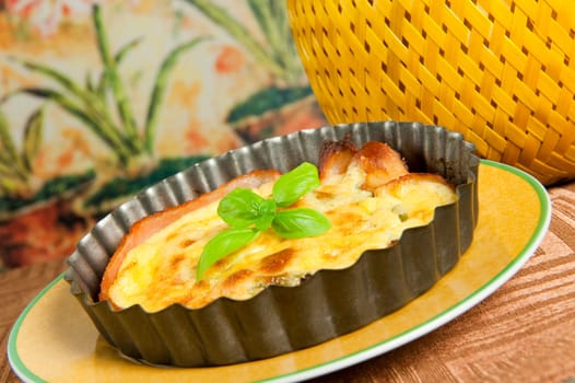 Eggs and bacon tart with basil leaves