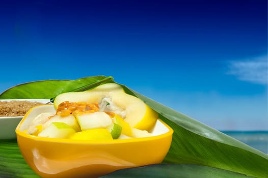 a salad with tropical fruits along the tropical sea