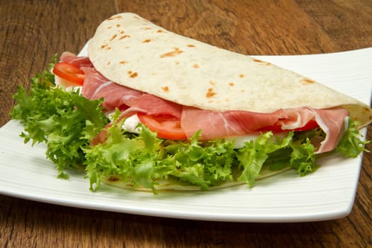 italian piadina with ham, fresh salad and mozzarella cheese