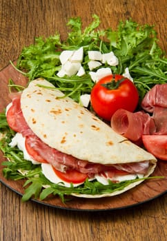 italian piadina with ham, fresh salad and mozzarella cheese