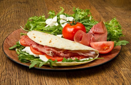 italian piadina with ham, fresh salad and mozzarella cheese