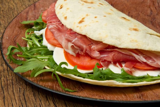 italian piadina with ham, fresh salad and mozzarella cheese